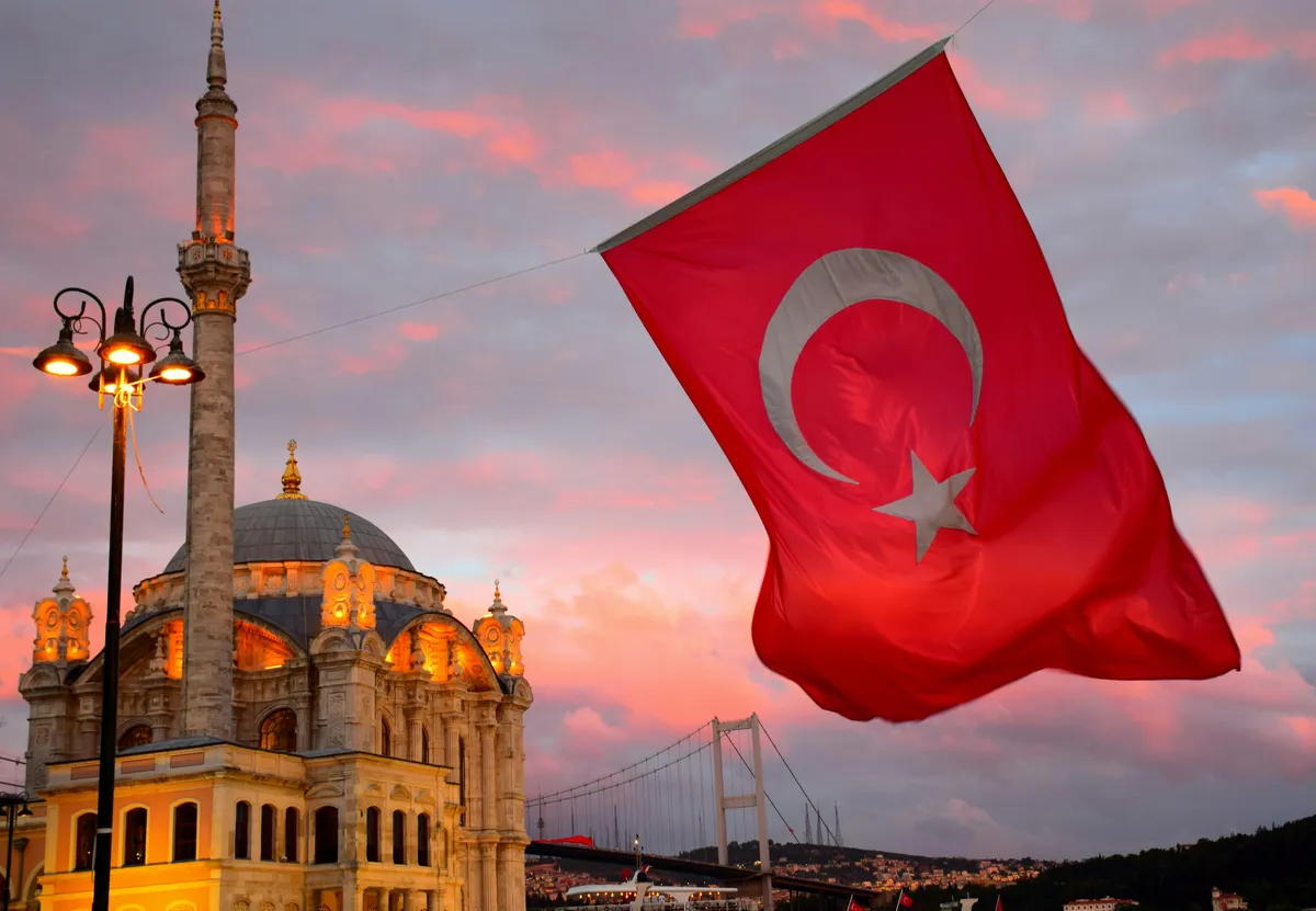 Turkish flag suspended from a wire against a sunset sky.