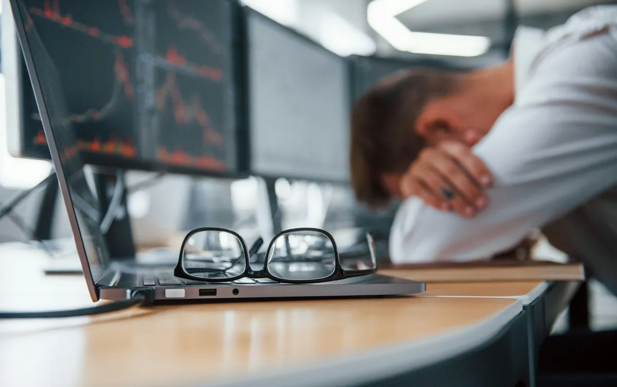 Crypto trader sleeping in front of chart screens (Unsplash)